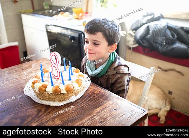 child turns eight years and blows out the candles of the cake