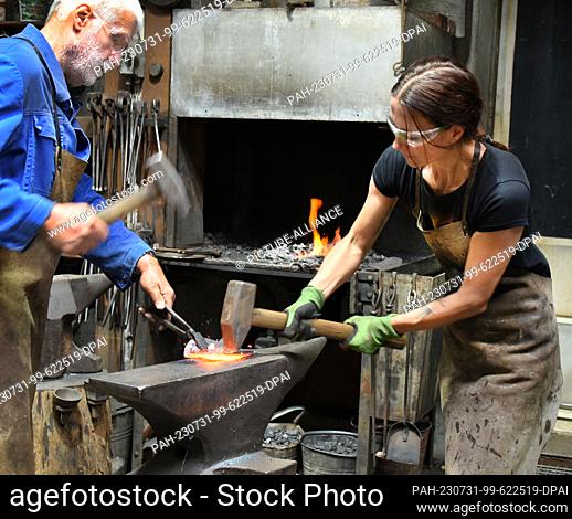 27 July 2023, Saxony, Hohenprießnitz: 39-year-old blacksmith and metal designer Marika Widdermann forges a lime leaf for a fruit bowl with her father Roger...