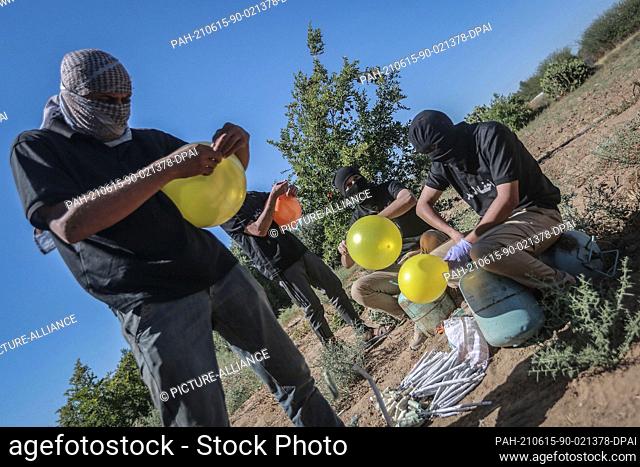 15 June 2021, Palestinian Territories, Gaza City: Masked Palestinians prepare to release refrigerant gas-filled balloons