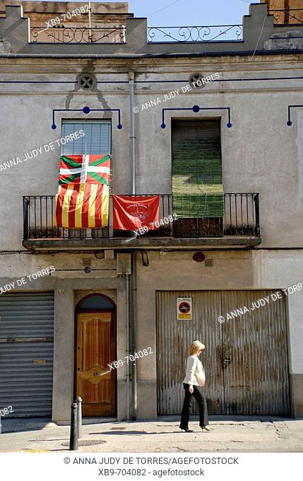 A woman walking in front of regional flags hung in protest on the Day of the Armed Forces of Spain