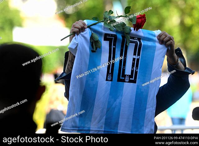 26 November 2020, Argentina, Buenos Aires: A fan holds up a jersey of the Argentine national football team with the number of Diego Maradona