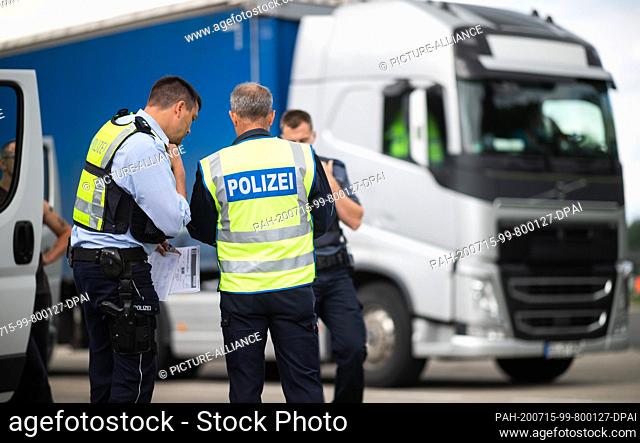 15 July 2020, North Rhine-Westphalia, Unna: Police officers are checking the papers of a truck driver at the Kolberg parking lot on Autobahn 2 in the direction...