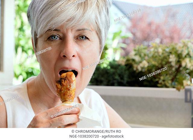 Woman biting into a freshly grilled chicken thighs