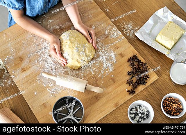 Hands of girl making dough on table