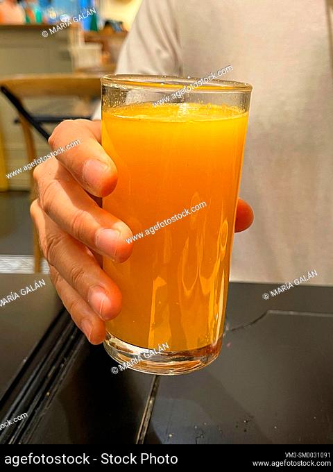 Hand holding a glass of orange juice