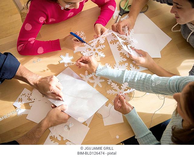 Caucasian family cutting out paper snowflakes