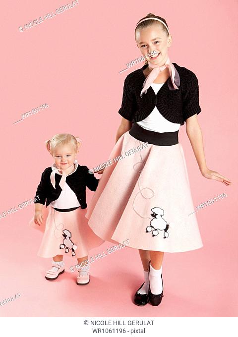 Portrait of girls (12-17 months) and (10-11) in 1950s style costumes for Halloween