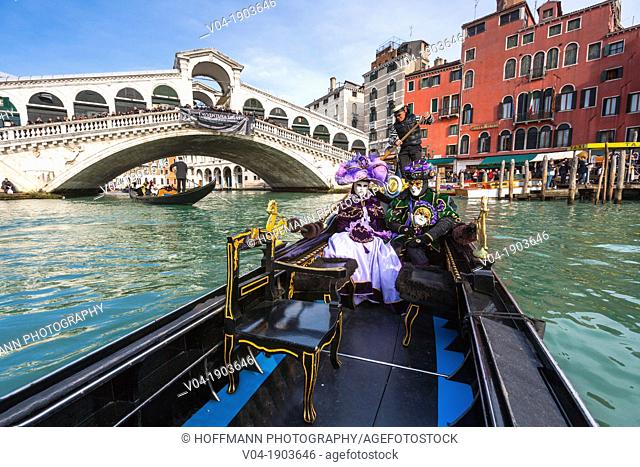 A masked couple in a gondola in front of the Rialto Bridge at the carnival in Venice, Italy, Europe
