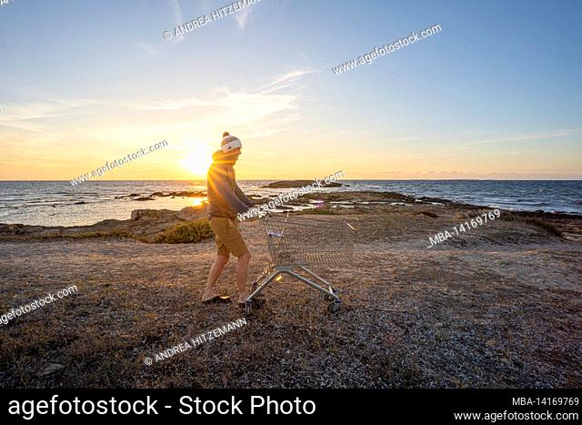 how much consumption can nature tolerate? man with shopping cart by the sea