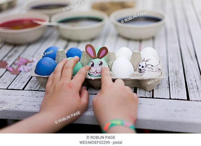 Close-up of girl decorating Easter egg on garden table