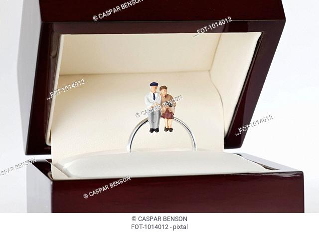 Miniature figurines of a senior woman and senior man sitting together on a wedding ring