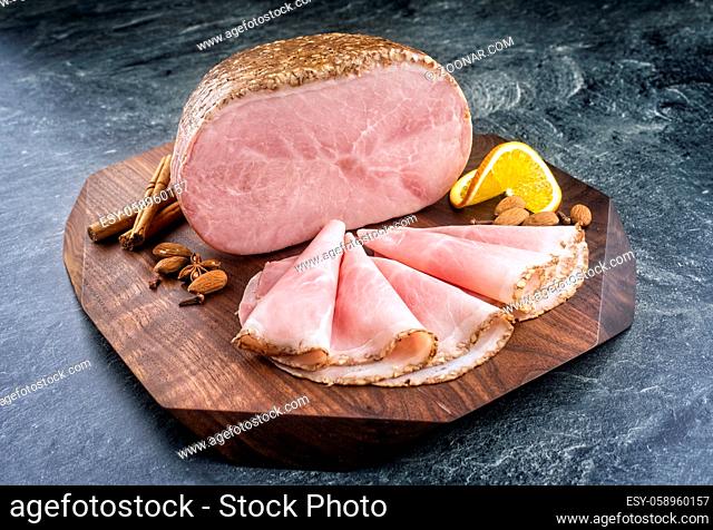 Traditional German boiled Christmas ham with almond, cinnamon and orange offered as close-up on a modern design wooden board with copy space