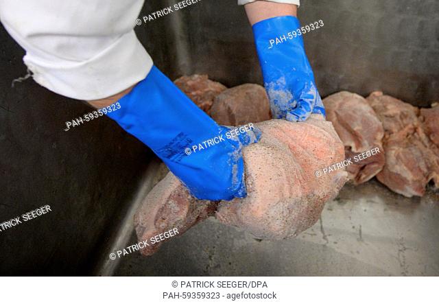 A file picture dated 24 October 2014 shows a butcher as he holds a leg of pork in his hands at ham manufacturer Adler in Bonndorf, Germany