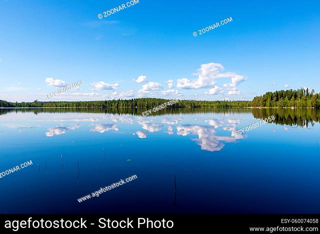 Sky reflects from still lake at summer day
