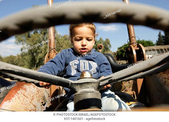 Toddler plays driver on an old tractor