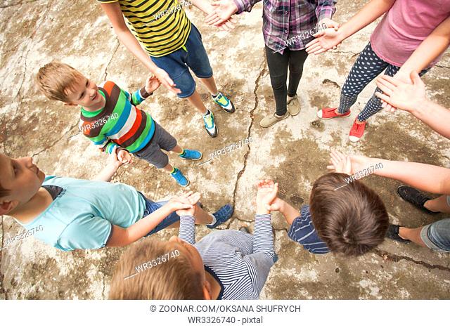 Children playing the game outdoors clapping hands in a circle