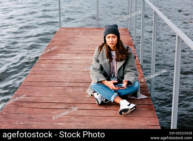 Young pretty girl on wooden bench on old pier. Cute Caucasian model
