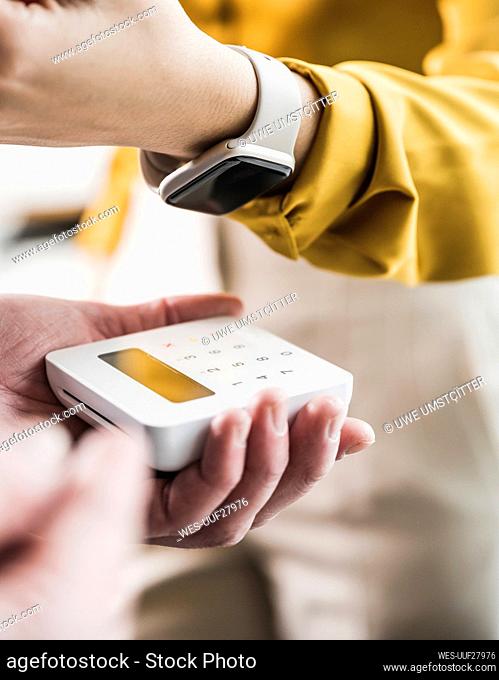 Young businesswoman paying with smart watch on credit card reader