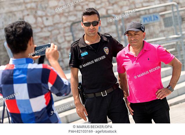 A man takes a photo with a police officer at Taksim Square in Istanbul, Turkey, 17 July 2016. Turkish authorities said they had regained control of the country...
