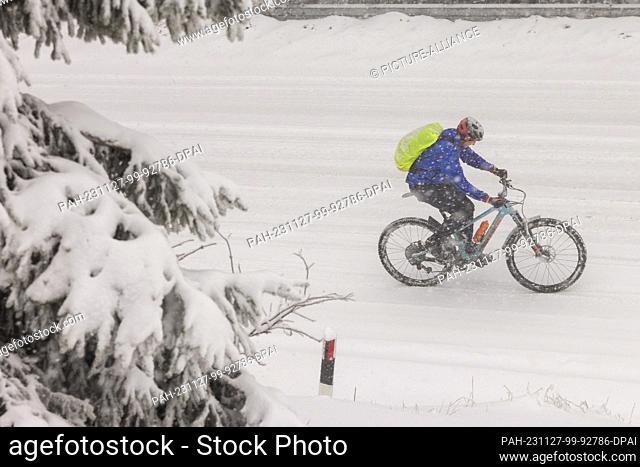 27 November 2023, Hesse, Feldberg: A cyclist is riding on the Großer Feldberg in the Taunus in snowfall. Photo: Helmut Fricke/dpa