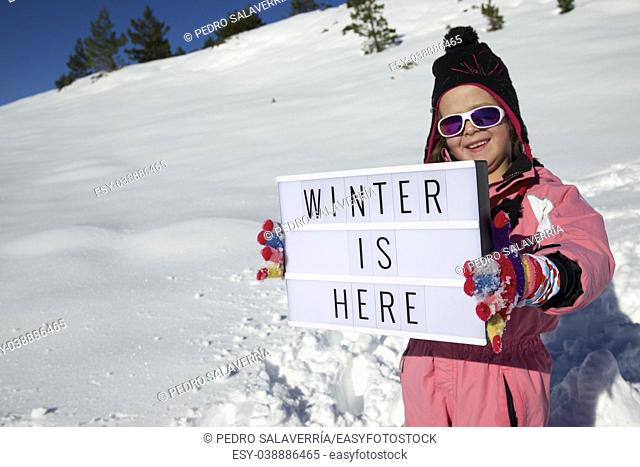 Slogan ""winter is here"" held by a girl in a snowy landscape