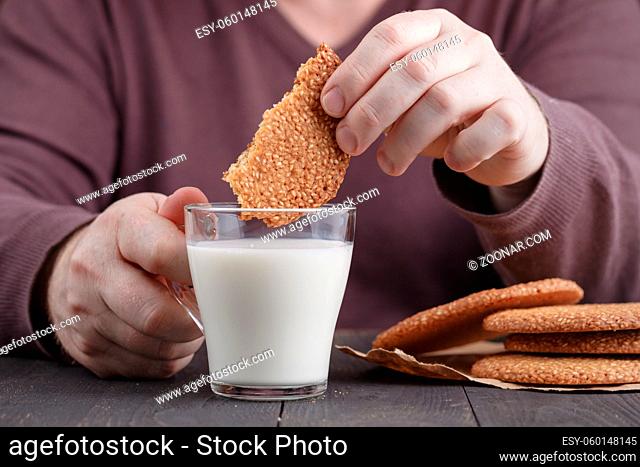 dunk sesame cookies biscuits in milk cup on table