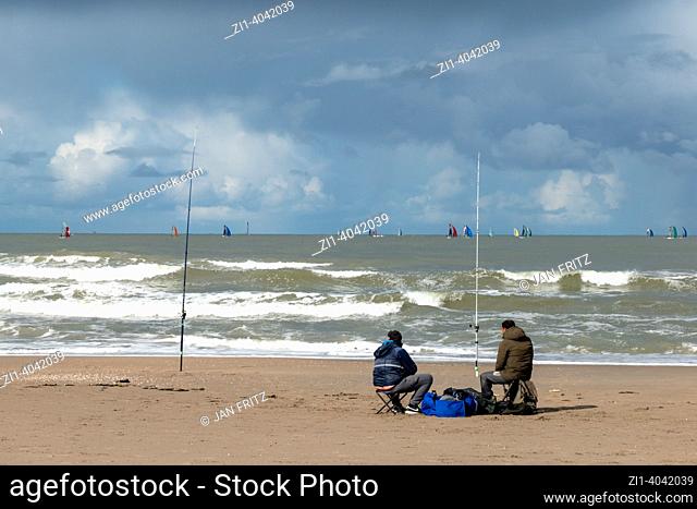 two fishermen at the beach and dark clouds above sea in Holland