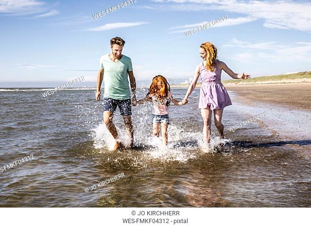 Netherlands, Zandvoort, happy family splashing in the sea