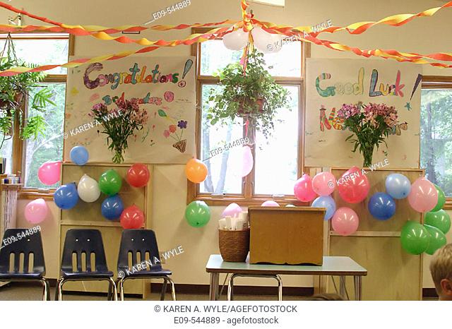 Classroom with 'Congratulations' and 'Good luck' banners, decorated with balloons and streamers, with row of empty chairs