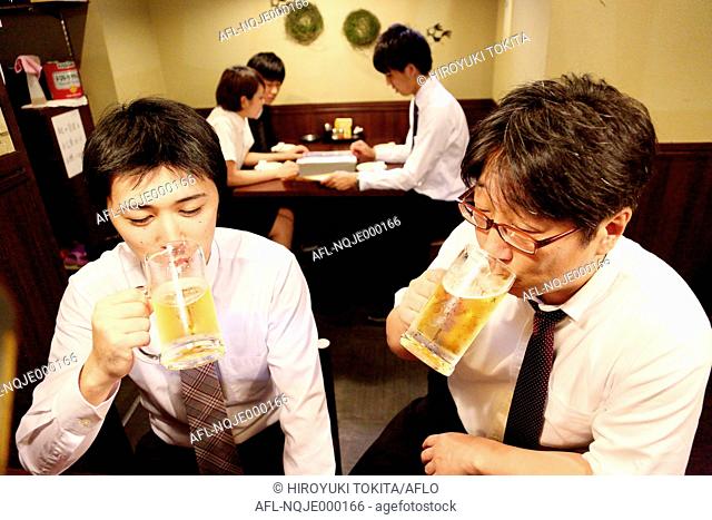 Japanese businessman drinking with his boss at a Japanese style Izakaya