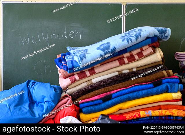 PRODUCTION - 07 April 2022, Saxony-Anhalt, Dessau-Roßlau: ""World Peace"" can be read on a board of a former school in front of which donated towels and...