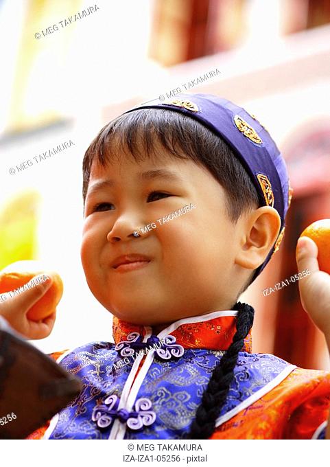 Close-up of a boy holding oranges and smiling