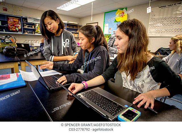 Asian American and Caucasian middle school STEM (Science, Technology, Engineering and Math) students use Google Chromebook laptops in science class in Mission...