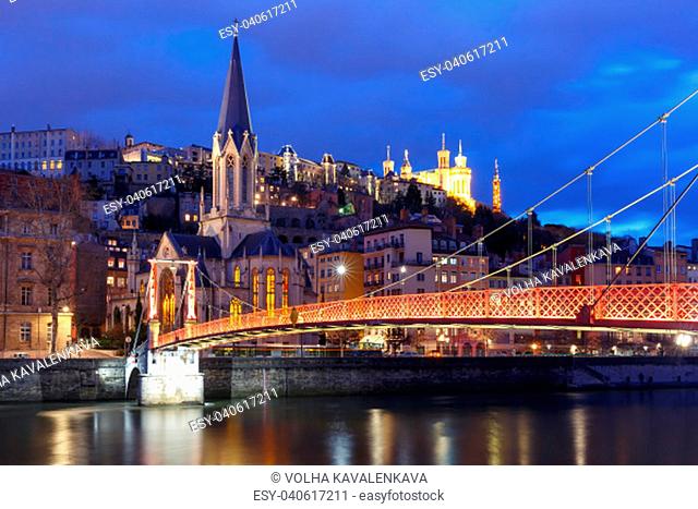 Panoramic view of Saint Georges church and footbridge across Saone river, Old town with Fourviere cathedral during evening blue hour in Lyon, France