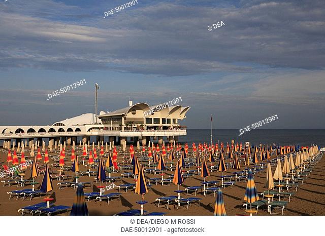 Italy - Friuli-Venezia Giulia Region - Udine Province - Lignano Sabbiadoro. Umbrellas and reclining chairs on the beach and pier Terrazza a Mare