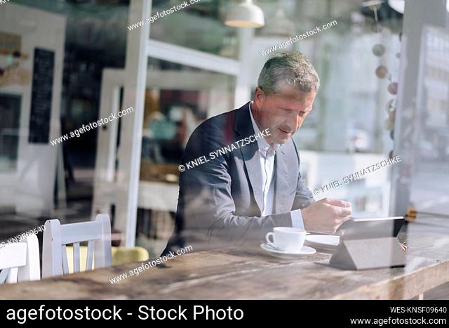 Businessman having breakfast and using tablet PC at cafe