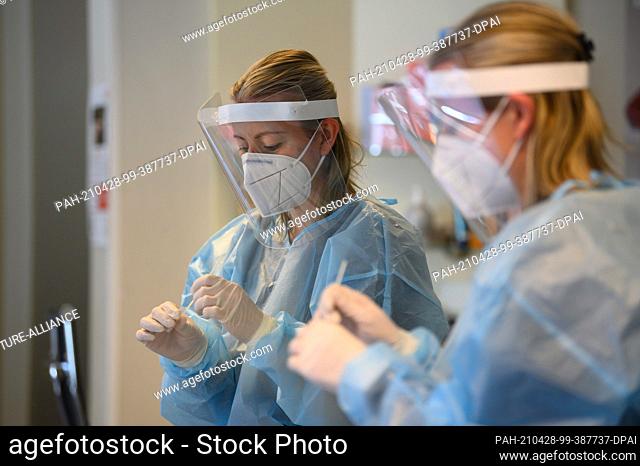 28 April 2021, Saxony, Dresden: An employee at the Holger Knievel hairdressing studio evaluates a rapid antigen test for the coronavirus