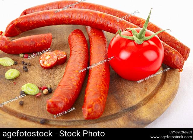 Spicy sausages and fresh tomato on wooden cutting bord