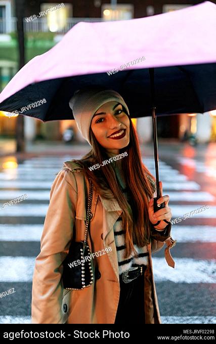 Woman holding umbrella standing on road in city