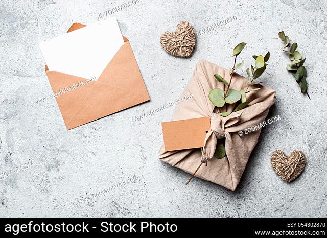 Zero waste Valentine's Day concept and mock up. Eco-friendly gift cloth wrapping in Furoshiki style, craft paper envelope, empty gift or greetings card