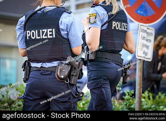 11 May 2022, Hessen, Hanau: Two female police officers are standing in front of a high-rise building where a dead girl was found in the morning