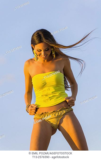 Fanciful young woman in swimsuit is laughing looking down at panties