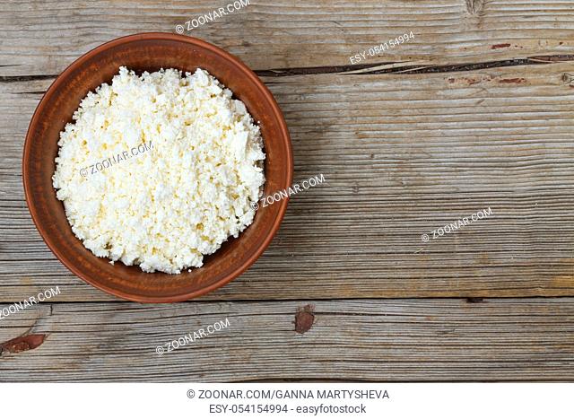 Fresh cottage cheese in a bowl on a wooden background