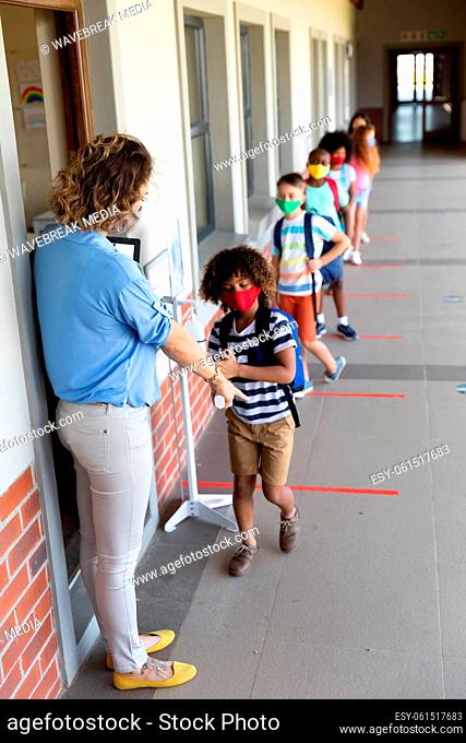 Female teacher wearing face mask pointing boy to stand on the marker