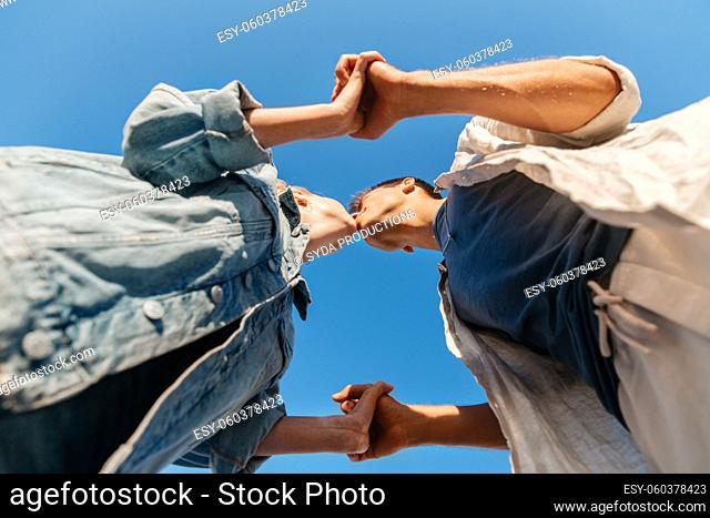 happy young couple kissing under blue sky