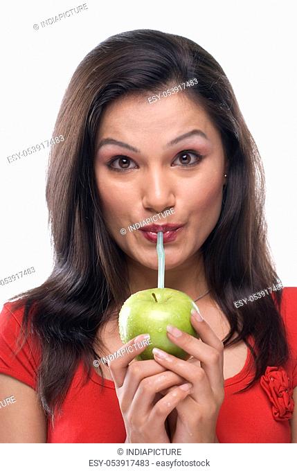 Woman sipping juice from an apple