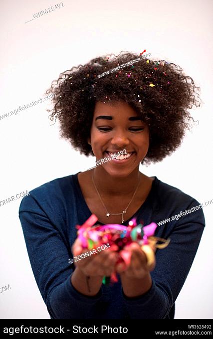beautiful young black woman celebrating new year and chrismas party while blowing confetti decorations to camera
