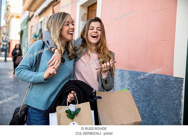 Friends out shopping and laughing in street