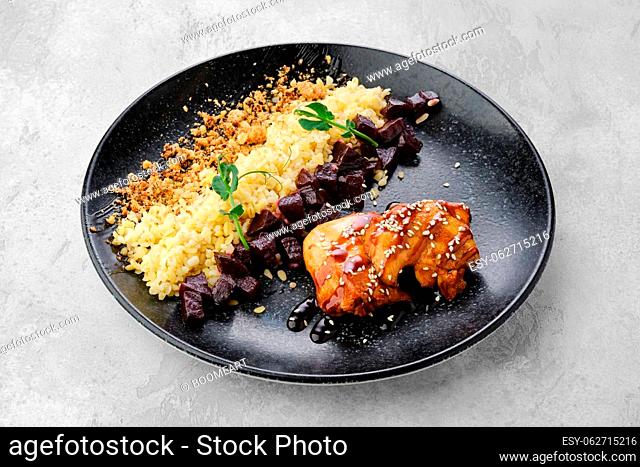 Fried chicken meat with teriyaki sauce and pearl barlew on a plate
