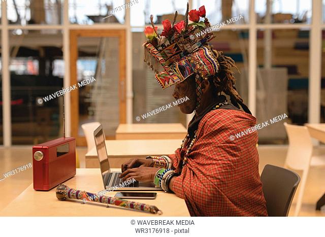 Maasai man in traditional clothing using laptop